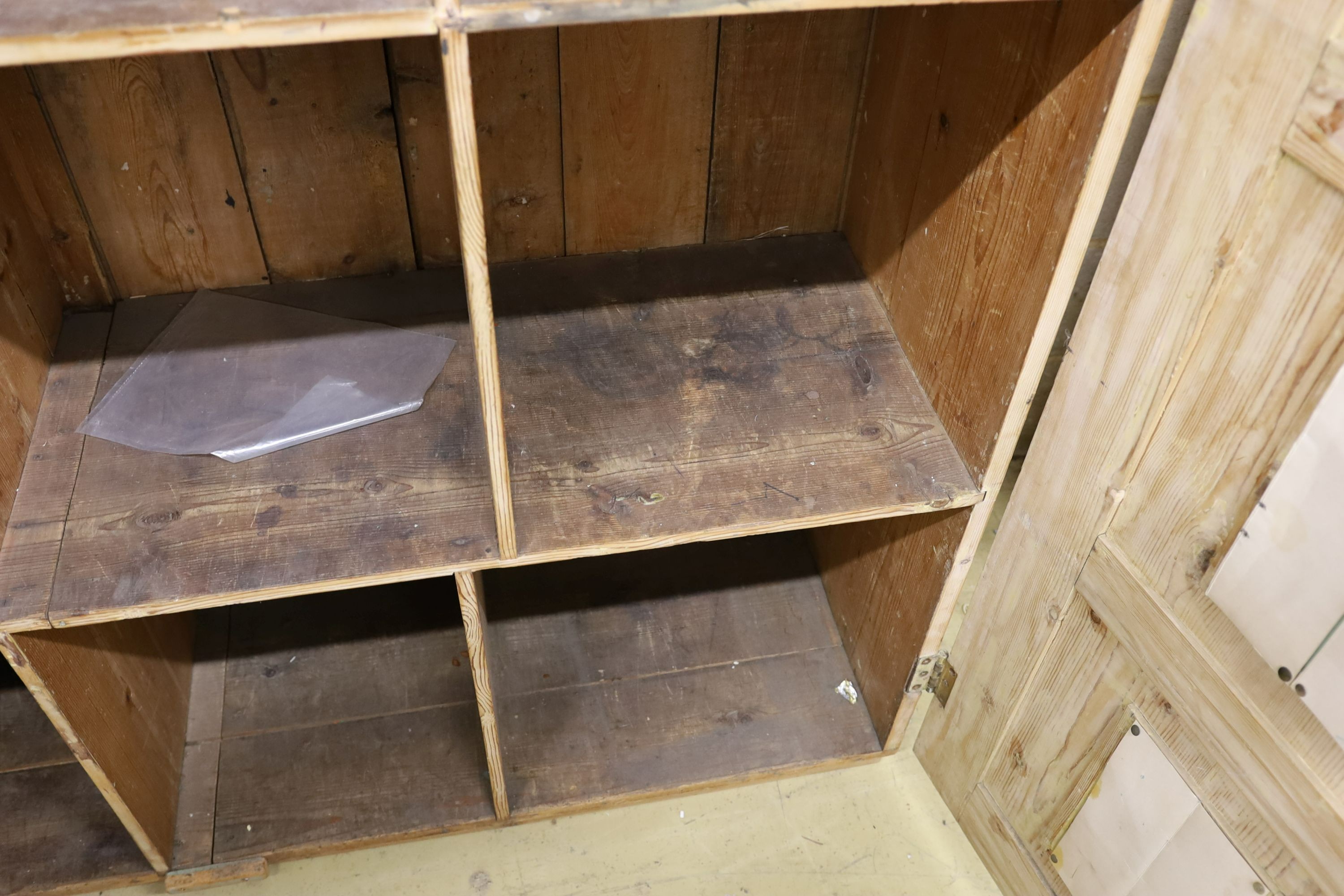 A 19th century stripped pine hall cupboard modelled as a dolls house the two door nine window facade enclosing a compartmented interior, width 182cm, depth 46cm, height 192cm